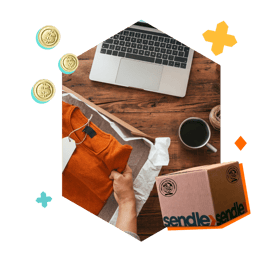 person with coffee and laptop on a table and putting shirt in a box