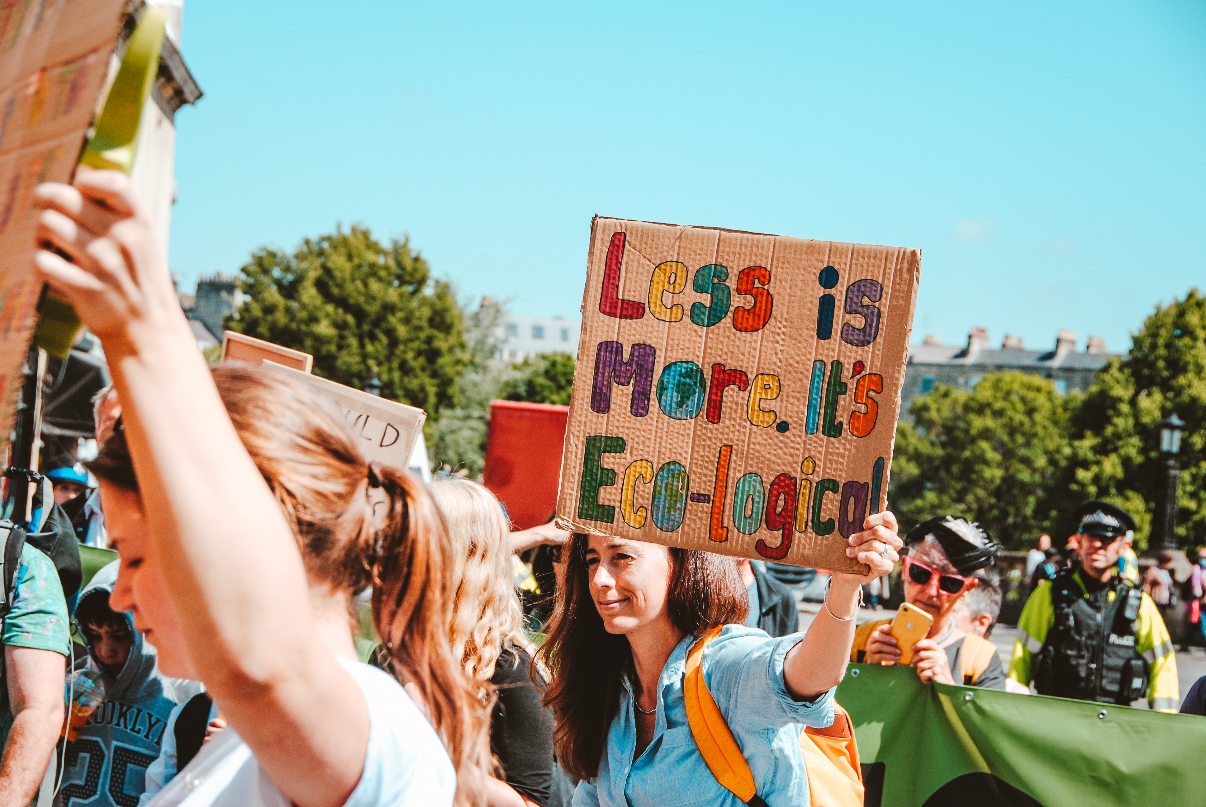 Woman holding a cardboard promoting eco-logical means along with many people in the rally