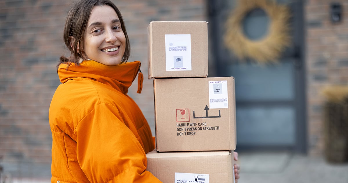 business woman holding boxes of packages for shipping outside the door