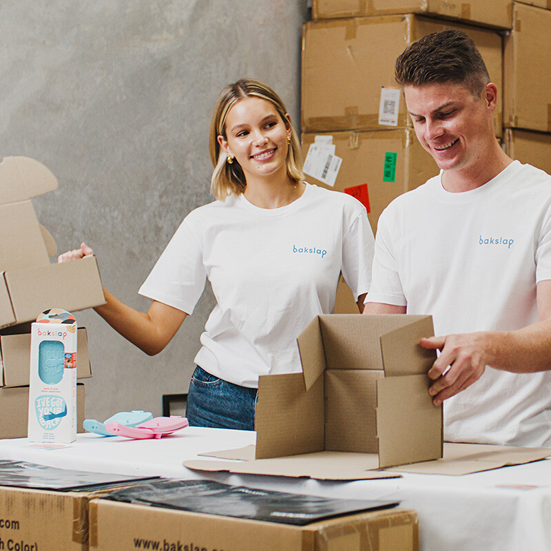 man and woman working packing bakslap products in boxes