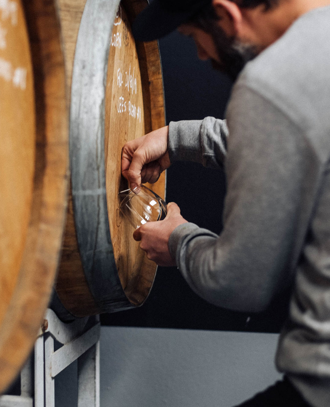 person pouring beer from barrel to glass
