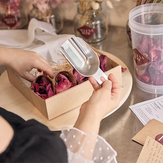 Helena Rose woman hands packing dried flower petals in the box