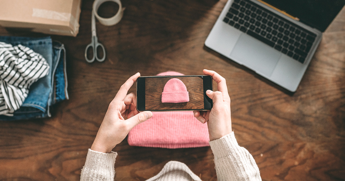 taking photo camera phone over pink beanie hat on wood table