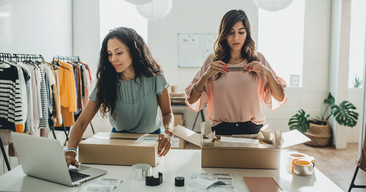 two woman small business working on laptop and taking photo of product