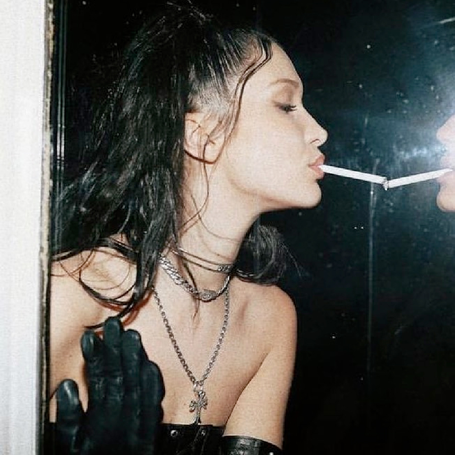 Bad Habkits a women eyes closed with cigarette in mouth facing a mirror