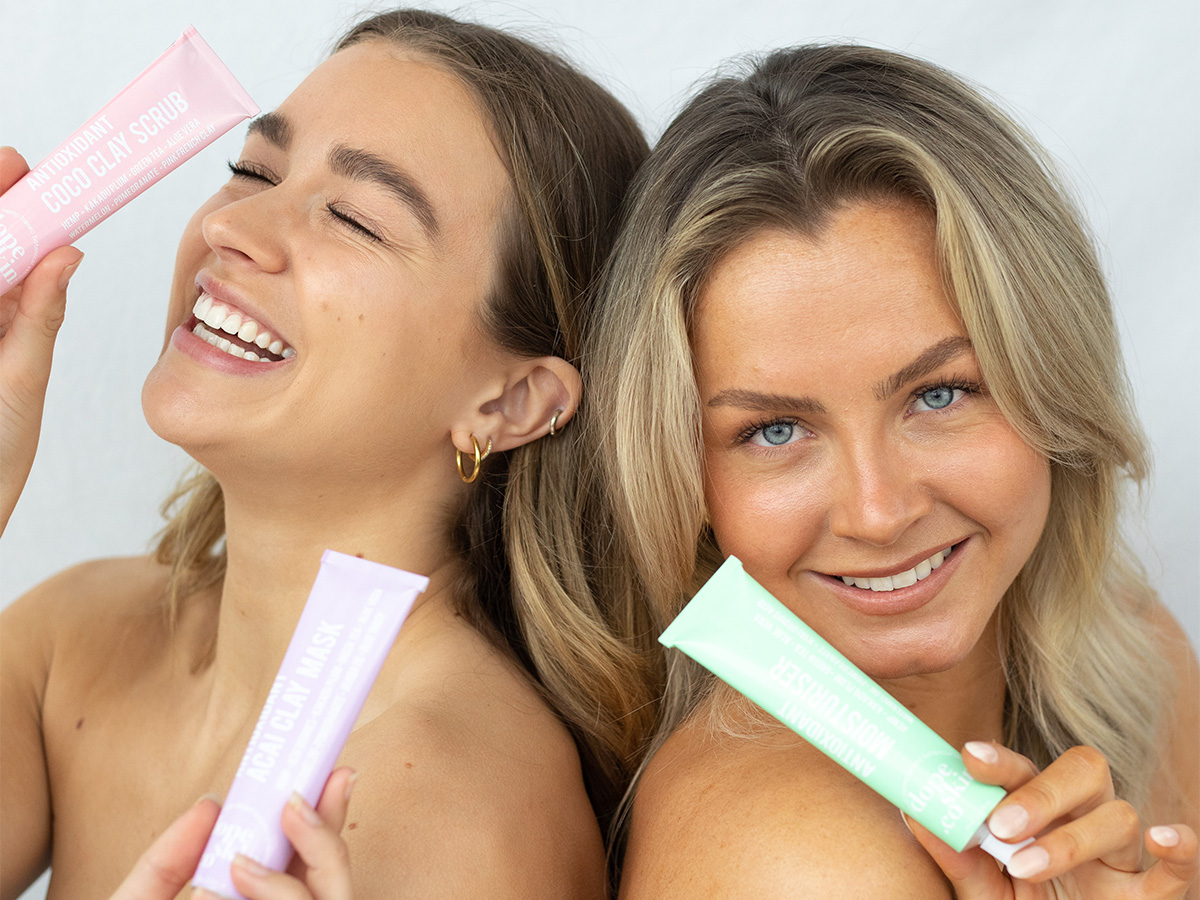two-women-smiling-happy-holding-skin-care-products-near-face