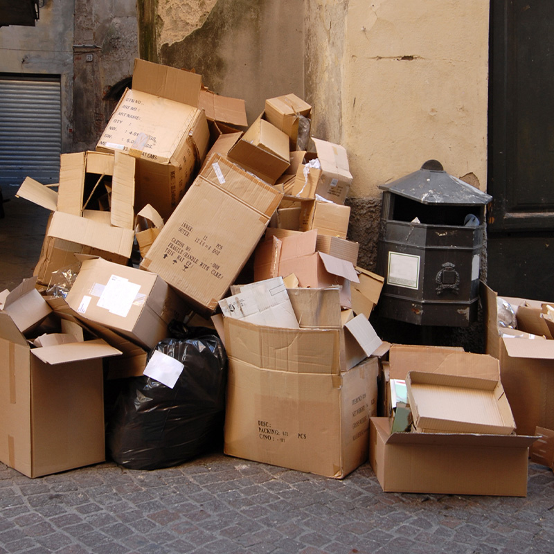 old cardboard boxes piled up around a trash bin in the street