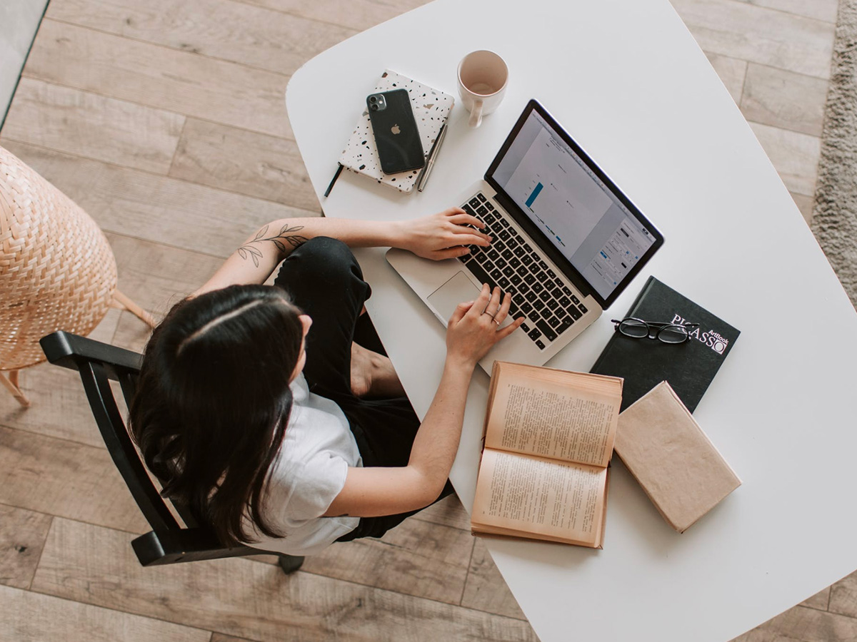 top view person sitting in front of desk working on laptop desk