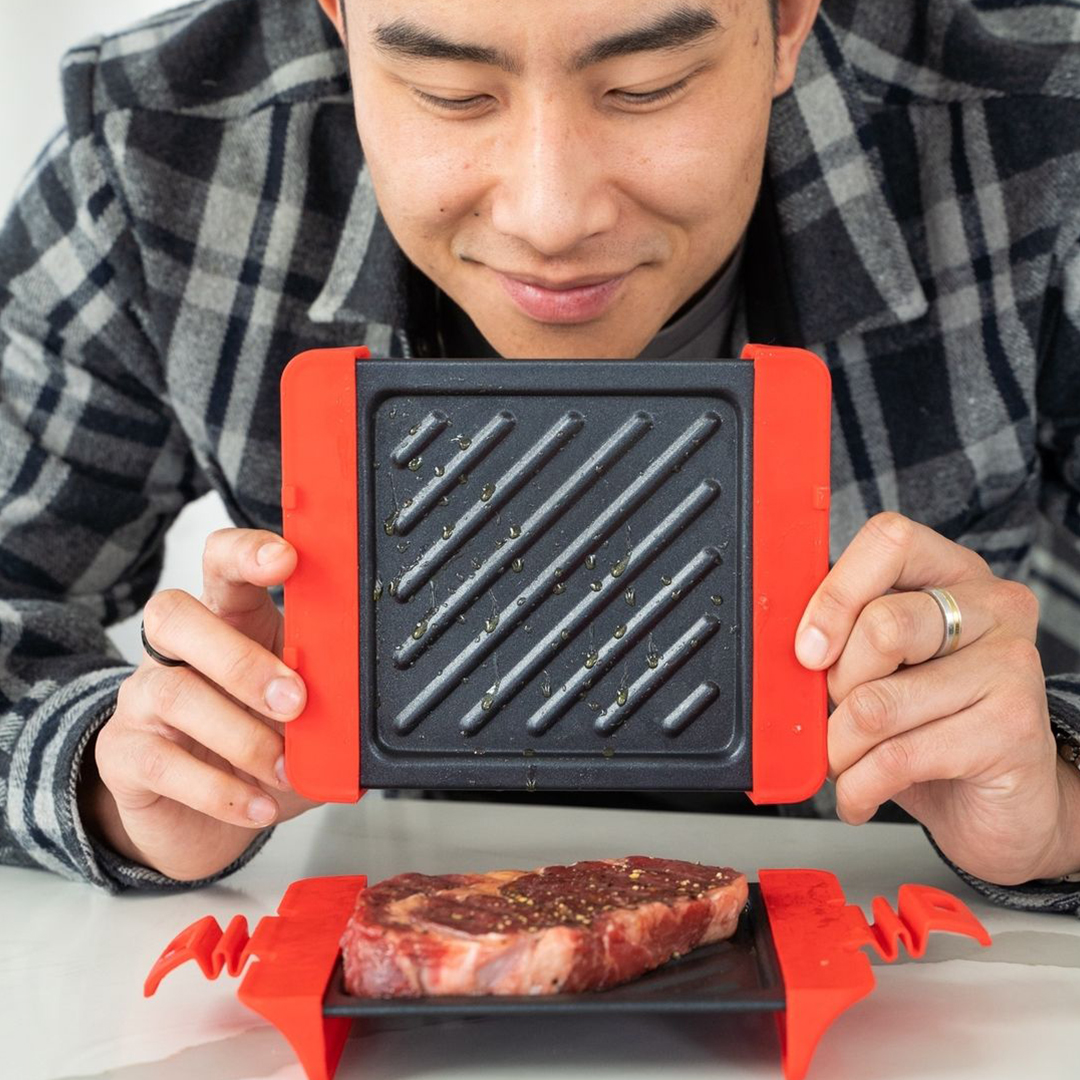 person cooking steak on microwave square grill