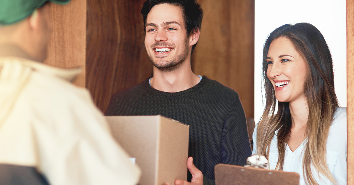 man and woman receiving box package at the door from a courier