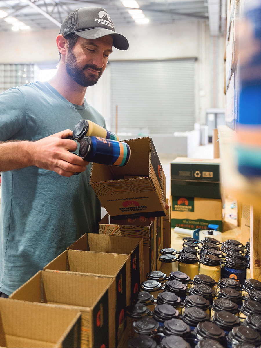 person packing cans of beer in boxes for shipping