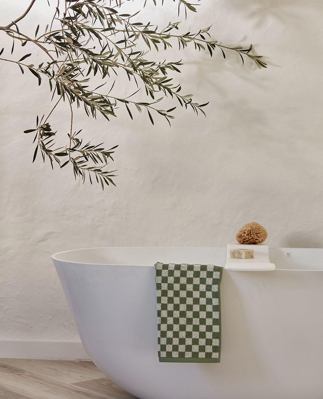 bathtray with loofah, handsoap and checkered towel on a bathtub