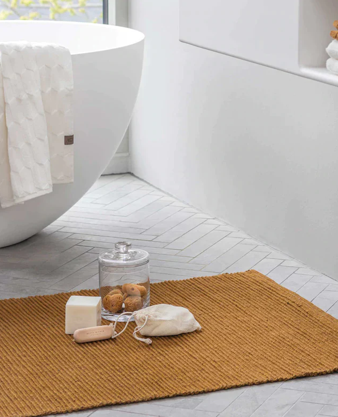 bathroom with towel on tub, soap and glass container on ribbon carpet