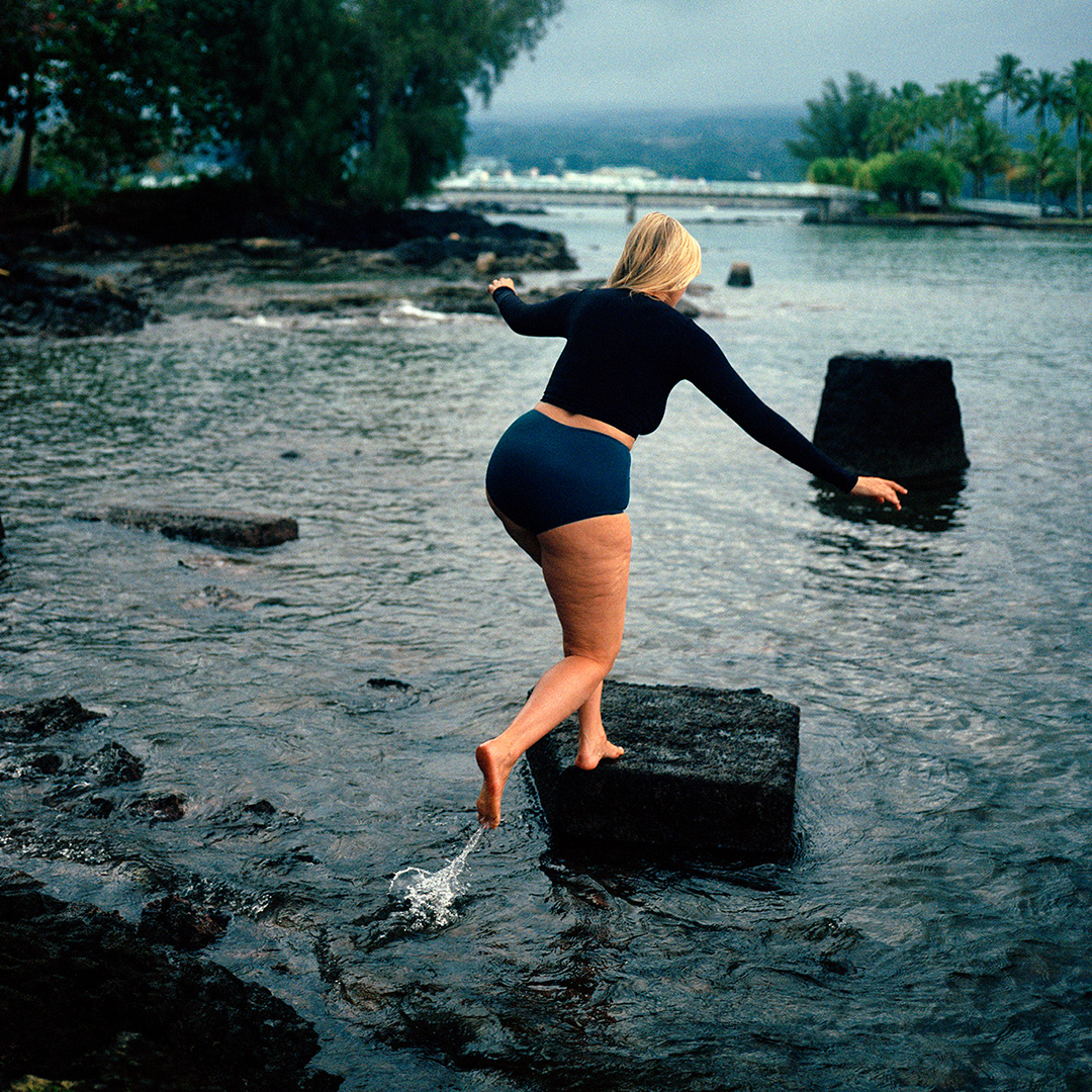 woman wearing pali swim swimwear jumping on big rocks in the river