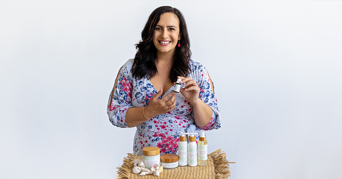 happy woman holding essental oil with various products in front of her on display