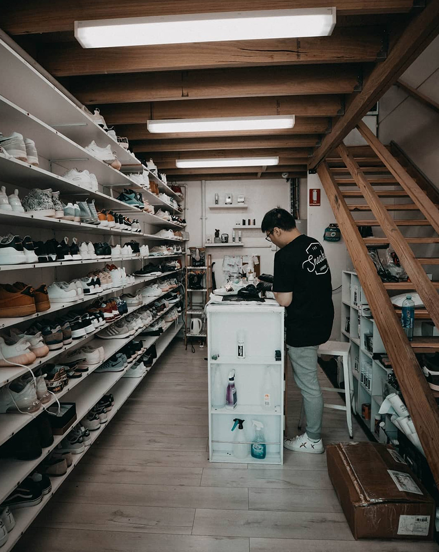 the sneaker laundry shop with a lot of shoes and a person cleaning