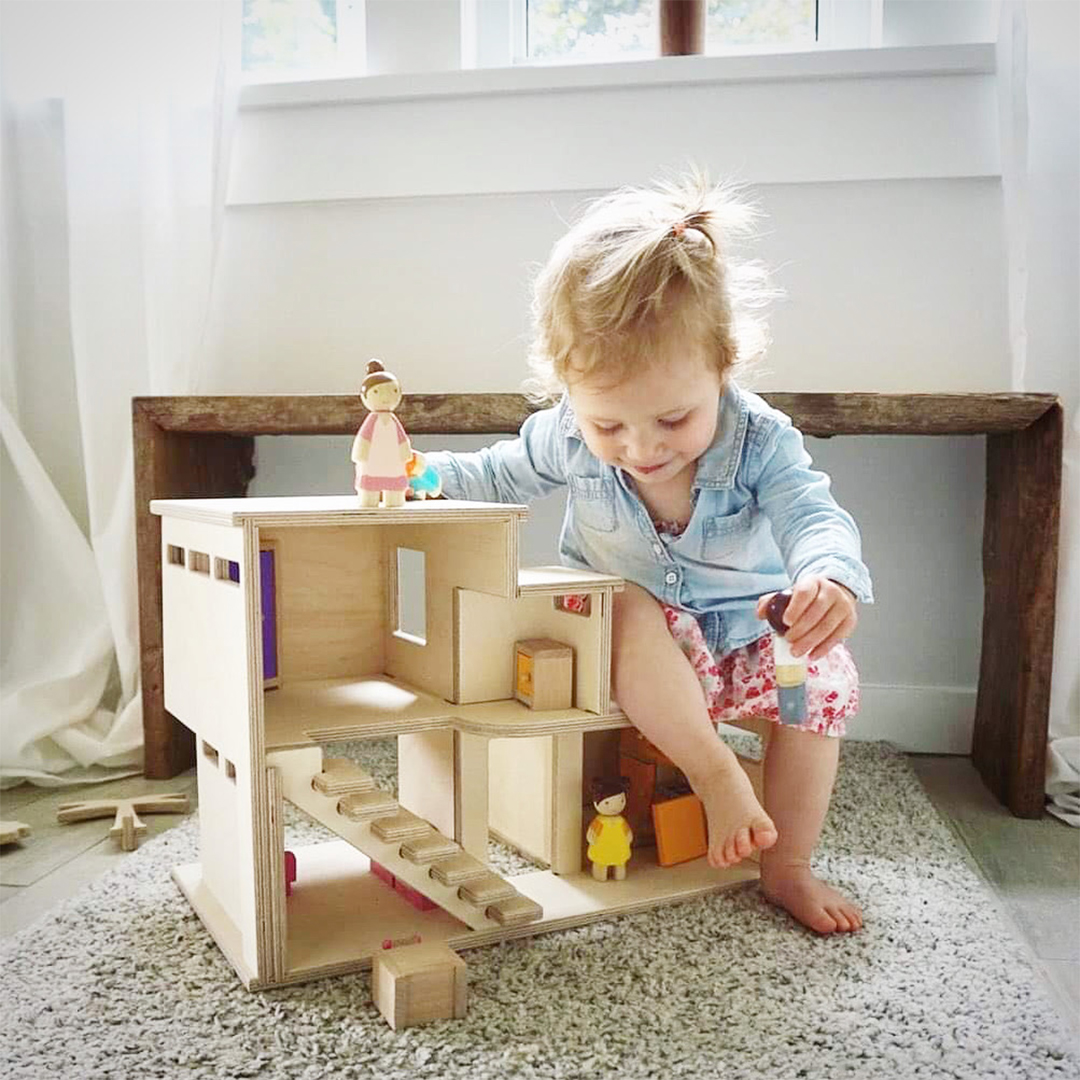 child playing with wooden playhouse