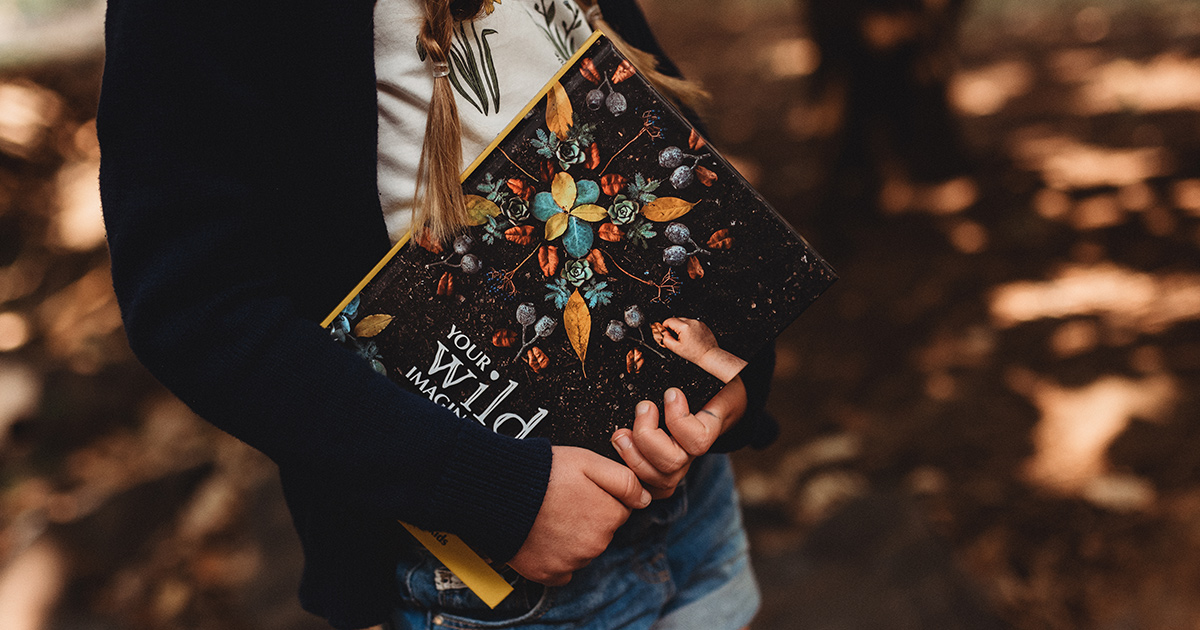 a child holding a book by your wild books